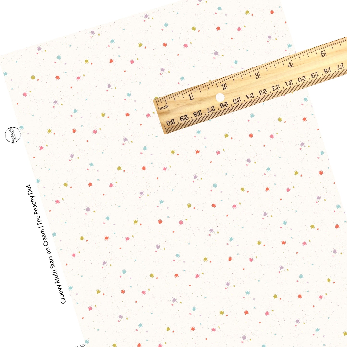 Colorful stars and speckles are scattered on a cream faux leather sheet. 