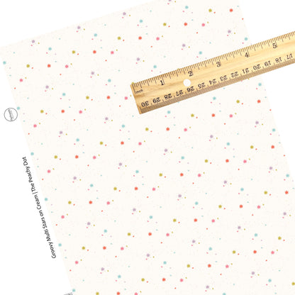Colorful stars and speckles are scattered on a cream faux leather sheet. 