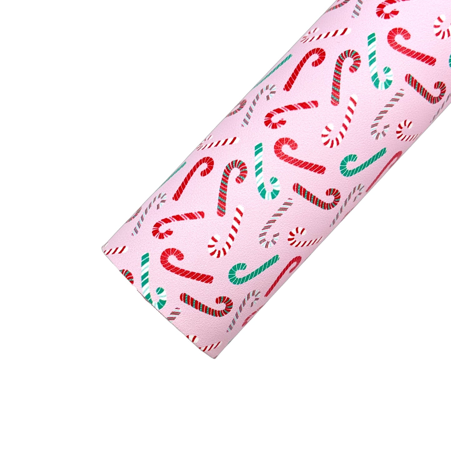 Rolled baby pink faux leather sheet with assorted red, green, and white candy cane pattern.