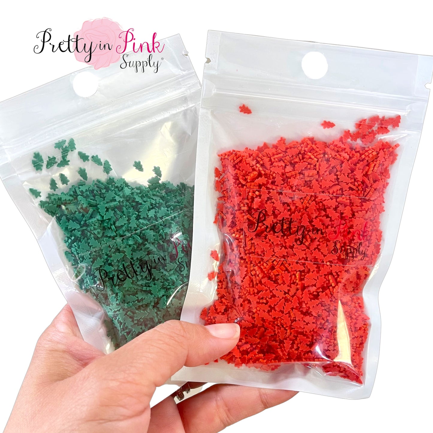 Hand holding bags of red and green Christmas tree clay slices.