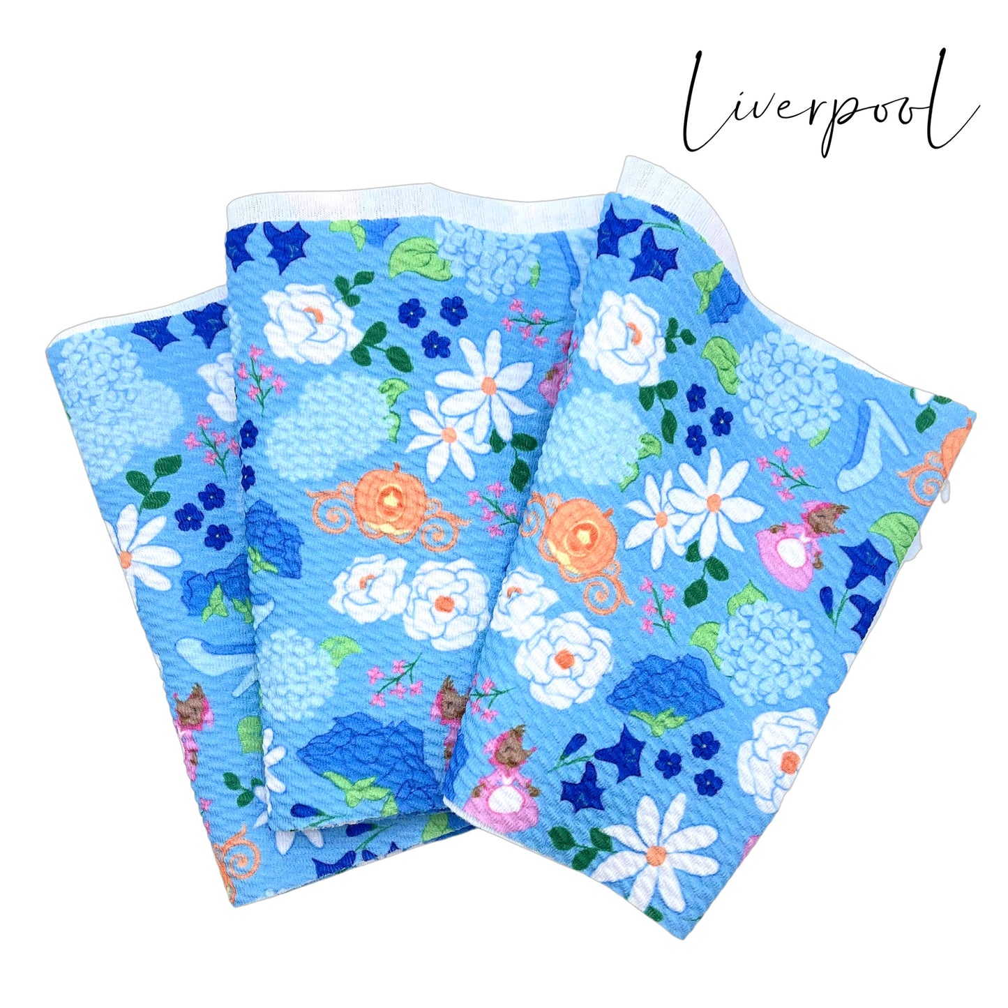 Folded light blue liverpool fabric strip with white, blue, navy, and baby blue princess floral pattern including a carriage, glass slipper, and female mice.
