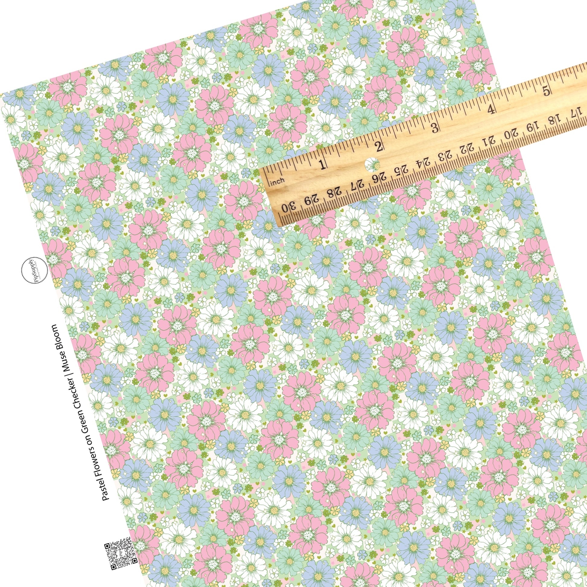 Pastel colors in pink, green, blue, and white flowers of various sizes on a green and pink and cream checkered pattern faux leather sheet. 