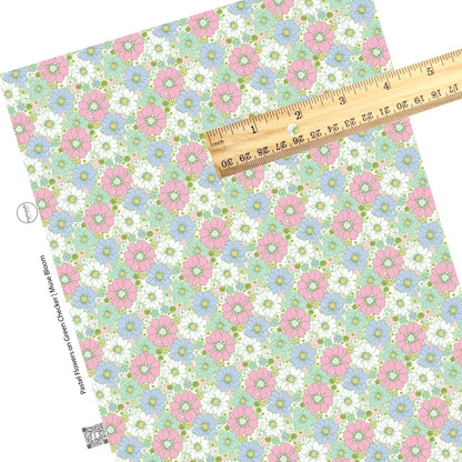 Pastel colors in pink, green, blue, and white flowers of various sizes on a green and pink and cream checkered pattern faux leather sheet. 