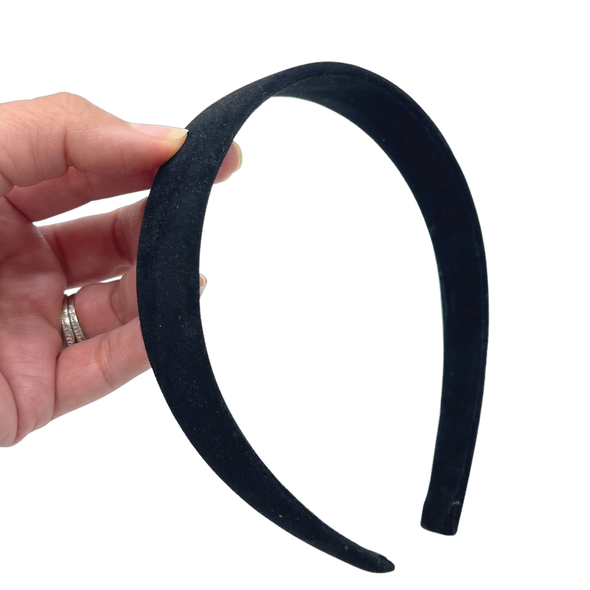 Hand holding black suede velvet lined headband.