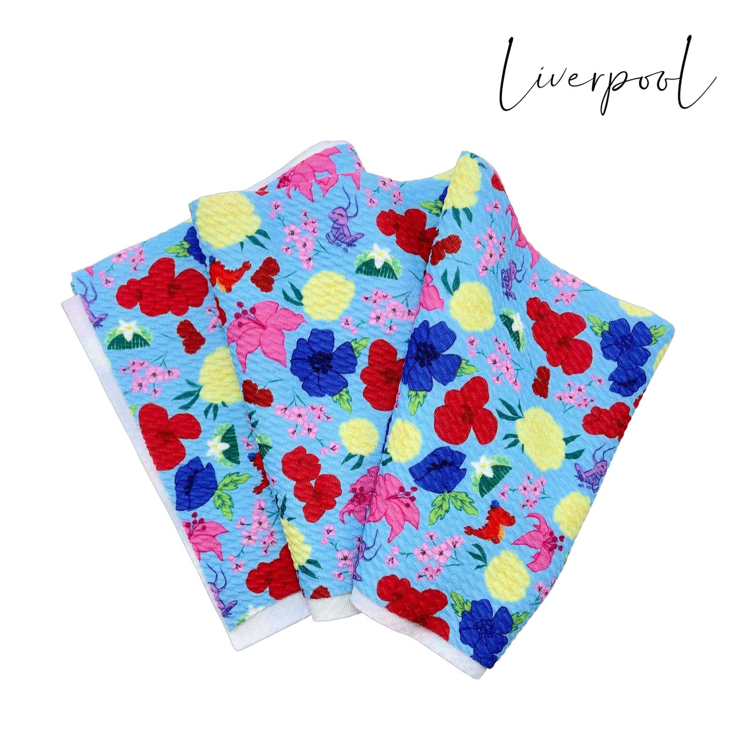 Folded light blue liverpool fabric with yellow, pink, royal blue, and red floral princess pattern including crickets, hair clips, and a red dragon.